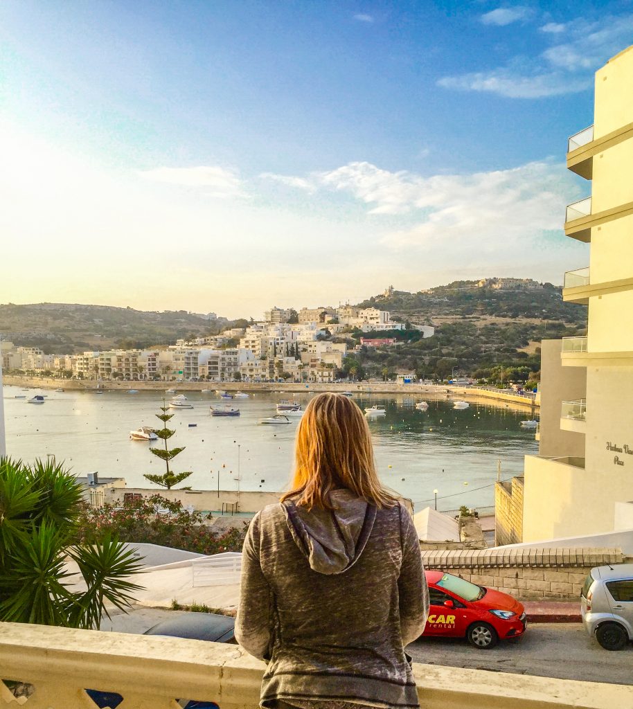 View of Me in front of St. Paul's Bay in Malta from our Balcony