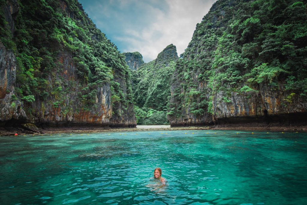 Me swimming in teal waters with limestone cliffs in Thailand
