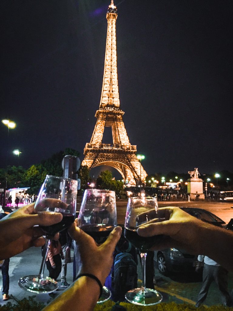 3 wine glasses cheersing in front of Eiffel Tower
