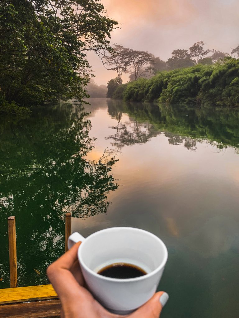 Cup of coffee and the sunrise over the Moho River in Belize