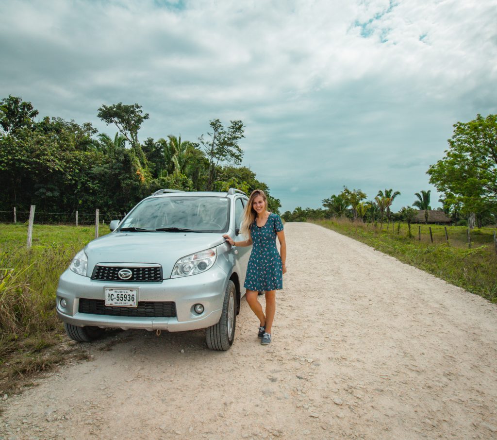 Me with our rental car on a dirt road in Belize
