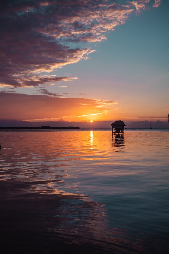 Sunset in the water with a shack by itself in Caye Caulker
