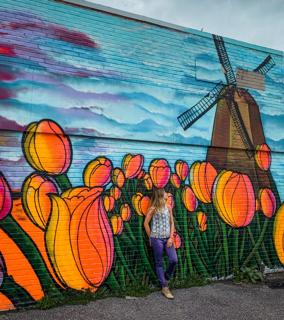 Me in front of a wall mural with tulips and a windmill